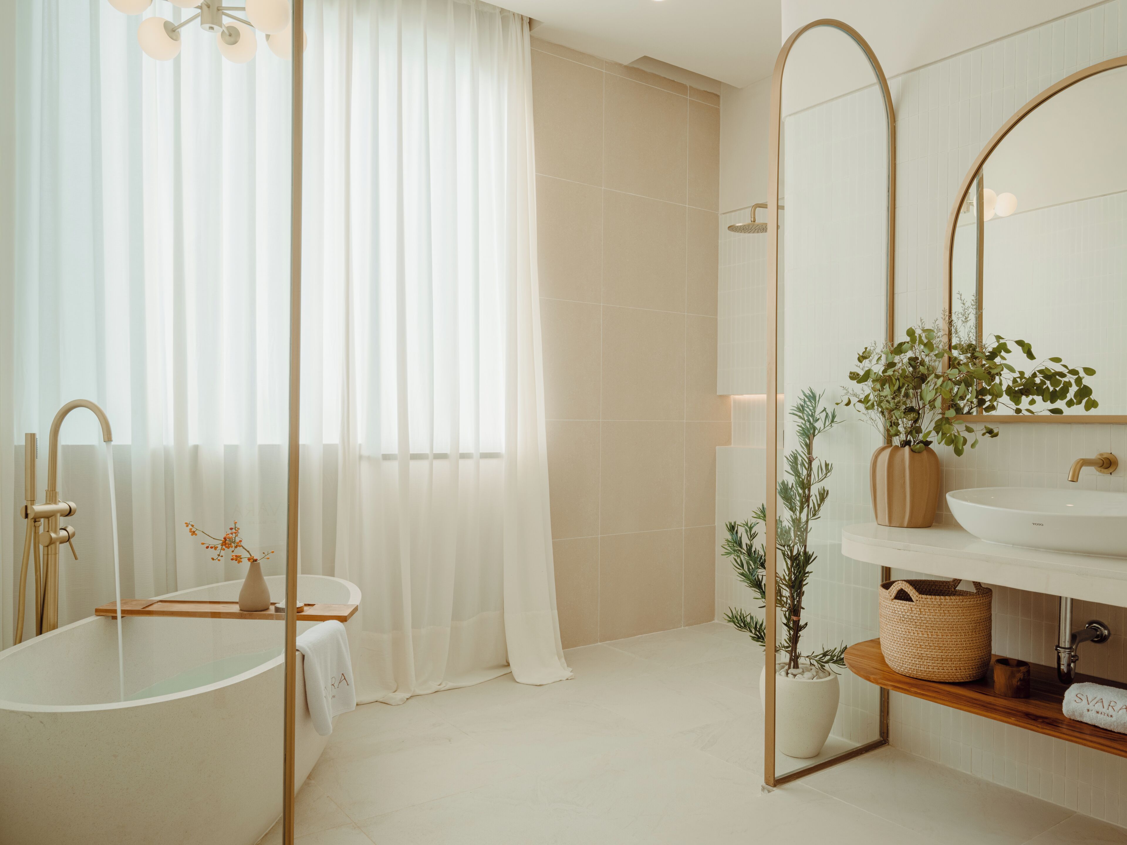 Ein modernes Badezimmer mit einer freistehenden Badewanne, einem großen Spiegel und einer Topfpflanze.