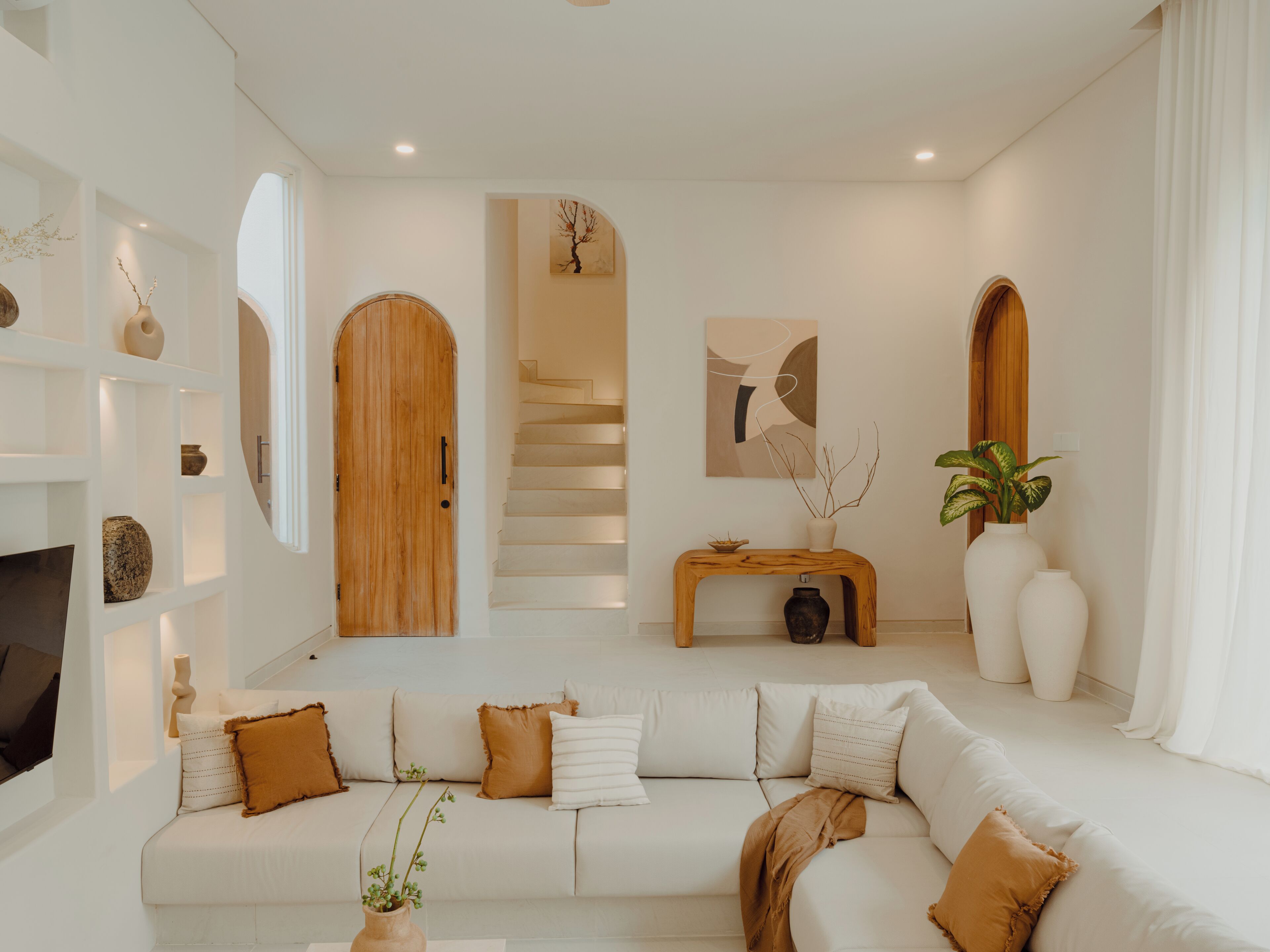 Ein modernes Wohnzimmer mit einer Couch, einer Holztür, einer Treppe und einem Bild an der Wand.