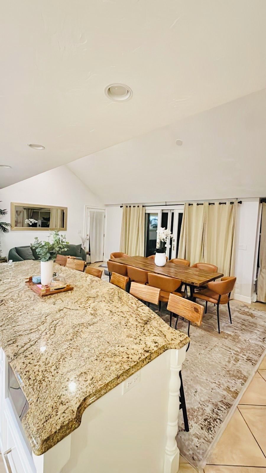 A kitchen with a granite countertop, wooden dining table, and chairs.