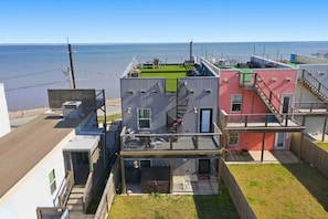 Ein Wohngebäude mit Dachterrasse, einer kleinen Außen-Sitzgelegenheit und einer Treppe zu einem Balkon im zweiten Stock.