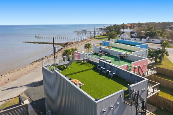 Un toit-terrasse agrémenté d’une pelouse verdoyante, d’un espace salon extérieur et offrant une vue sur la mer.