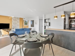 A modern kitchen with a central island, a dining area with a glass table, and a living room with a blue sofa. - 4★ Apartment • Sea View • Pool • 2 Bedrooms • Garage (Saint-Raphaël)