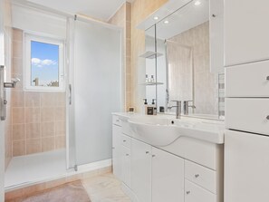 Une salle de bain moderne dotée d’une douche à l’italienne, d’un grand miroir et d’un meuble-lavabo.