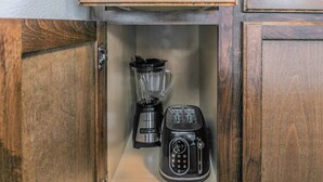 Um armário de cozinha com um liquidificador e uma torradeira.