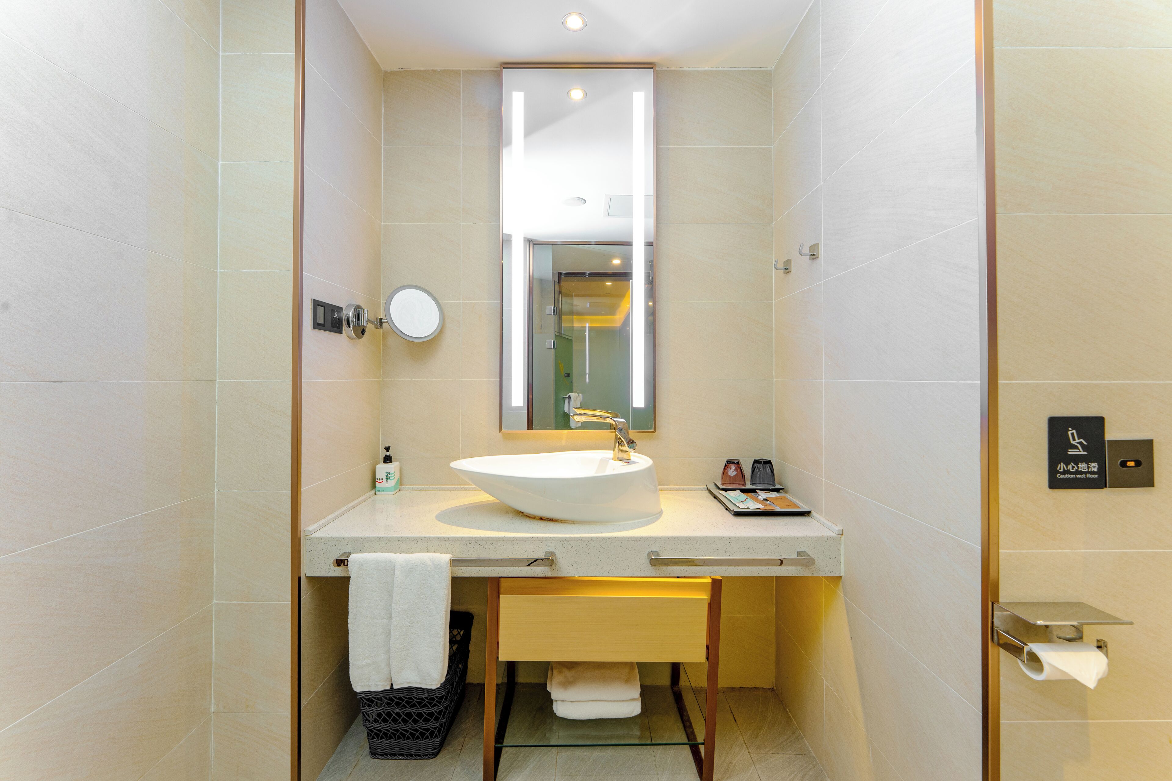 A modern bathroom with a large sink, mirror, and towel rack.