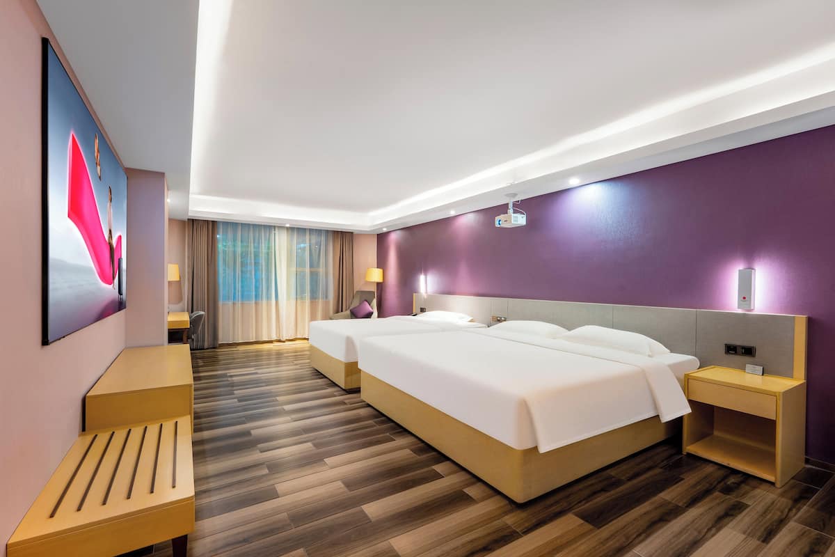 Camera d'albergo con due letti, una scrivania, una sedia, una lampada e un quadro di grandi dimensioni appeso al muro.
