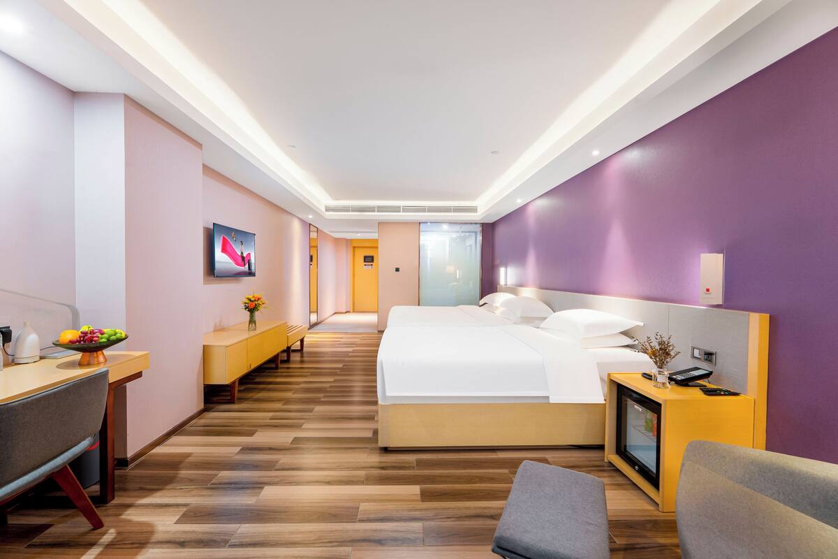 Camera d'albergo moderna con letto, comodino, scrivania e vista sul corridoio.