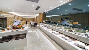 A modern hotel dining area with a buffet setup, including various dishes and utensils. - Trendy Romantic MAXScreen Hotel (Guangzhou)