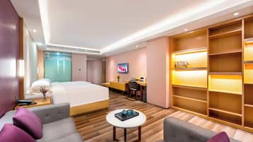 Una habitación de hotel moderna con cama, escritorio, televisor y zona de estar con una mesita de centro.