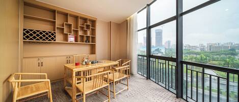 A modern room with a large window, a wooden dining table with chairs, and built-in shelving.