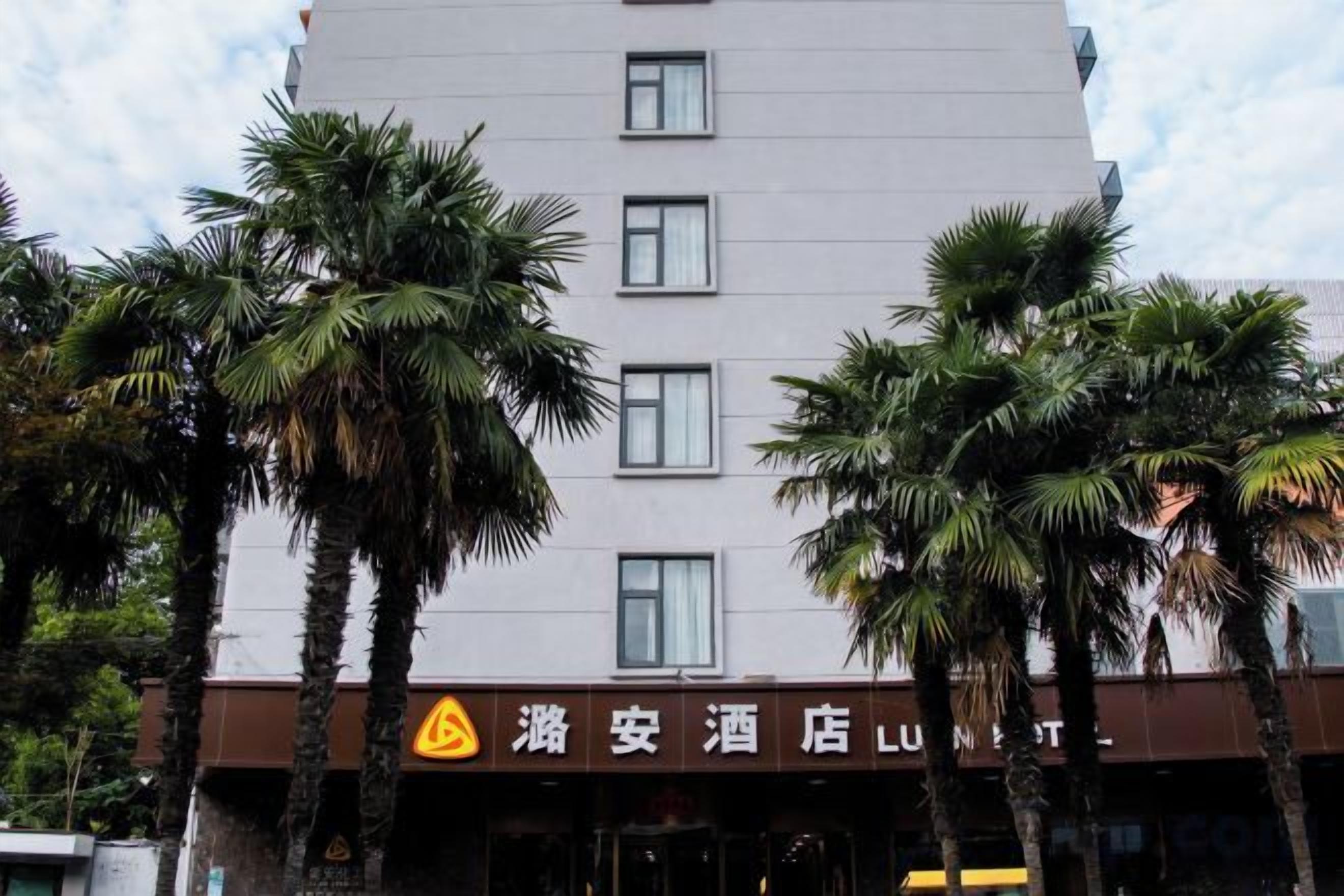 A hotel with a modern facade, palm trees in front, and a sign indicating it is a hotel.