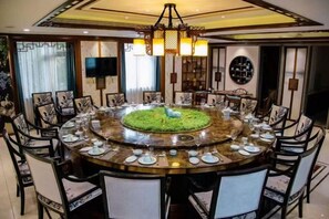 Une table de salle à manger ronde, avec des chaises, un élément décoratif central et un lustre.
