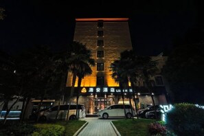A building with a prominent entrance, a parking area, and a well-lit facade at night. - Shanghai Lu'an Hotel (Ningguo Road) (Shanghai)