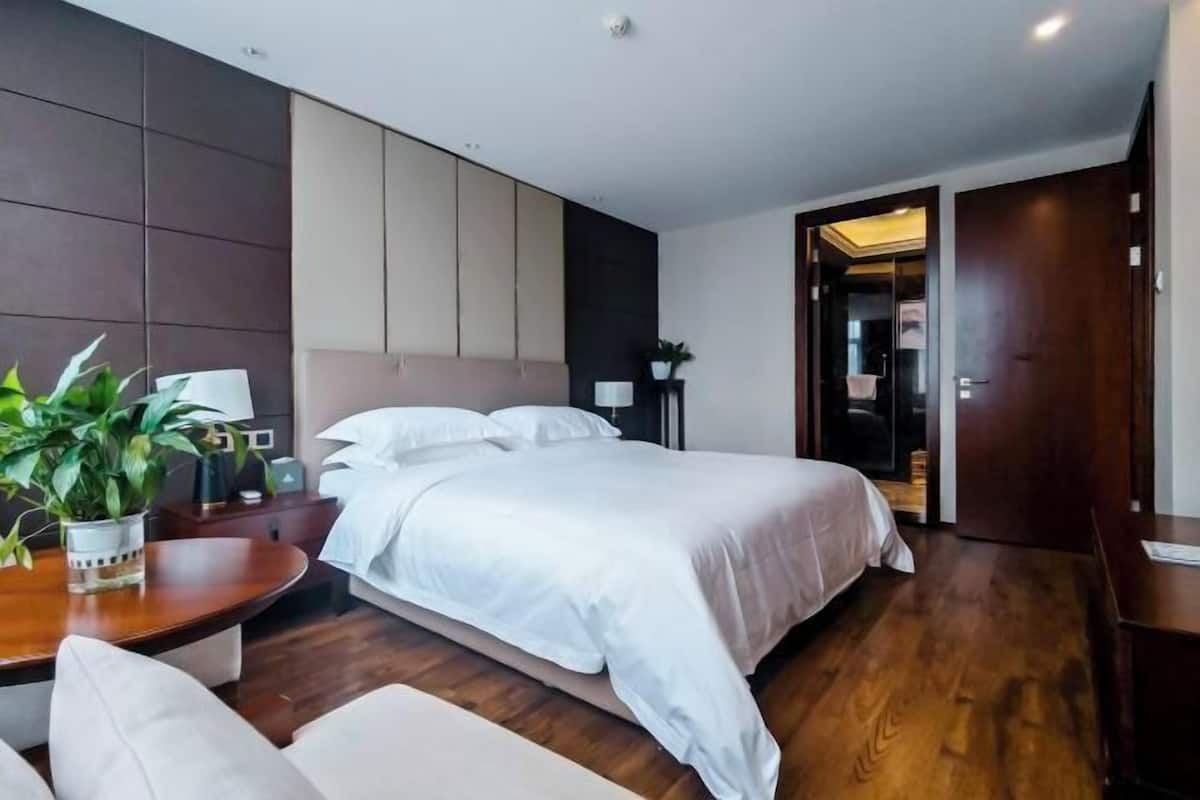 Una habitación de hotel moderna con una cama grande, mesitas de noche, un escritorio y una planta en maceta.