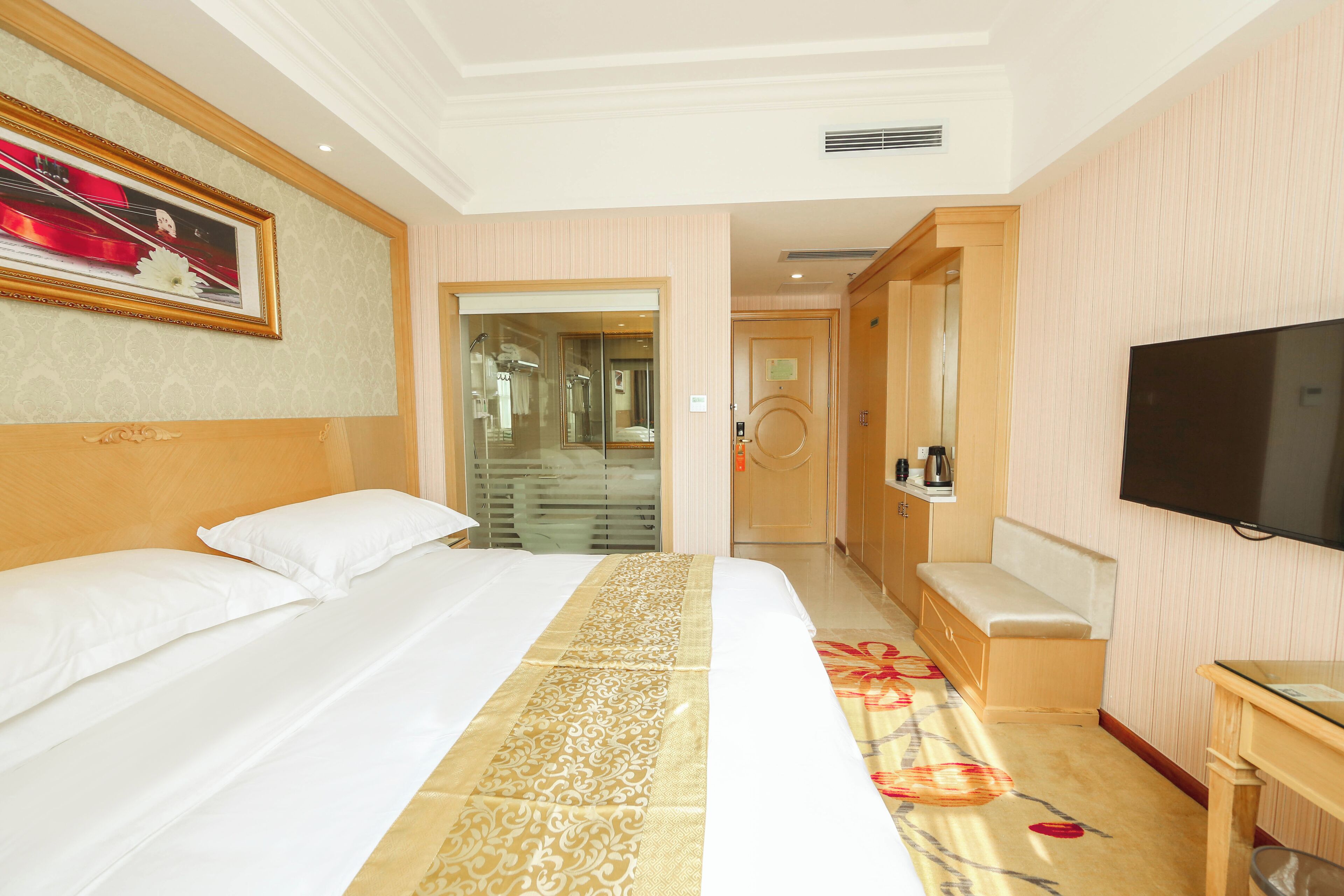 A hotel room with a large bed, a television, a sofa, and a desk.
