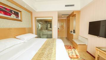 A hotel room with a large bed, a television, a sofa, and a desk.