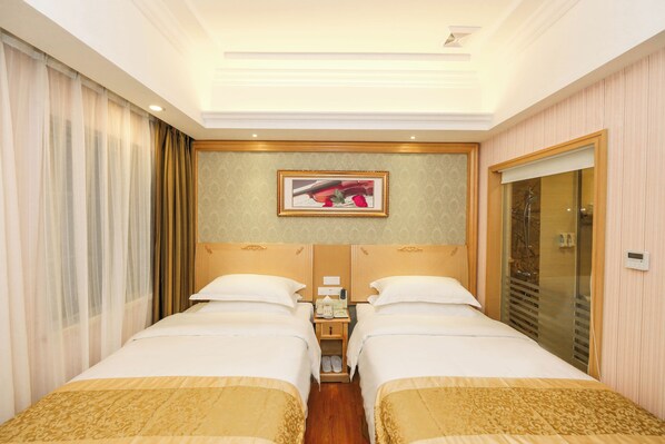 A hotel room with two beds, a nightstand, a framed picture on the wall, and a sliding door closet. - Vienna 3 Best Hotel Guangzhou Canton (Guangzhou)