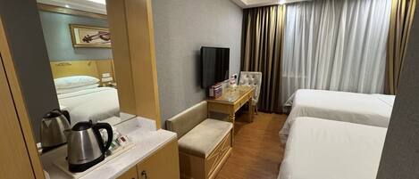 Een hotelkamer met een bed, een bureau met televisie, een minibar en een spiegel.