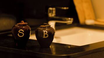 Two dark-colored ceramic containers with letters 'S' and 'B' on a kitchen counter.