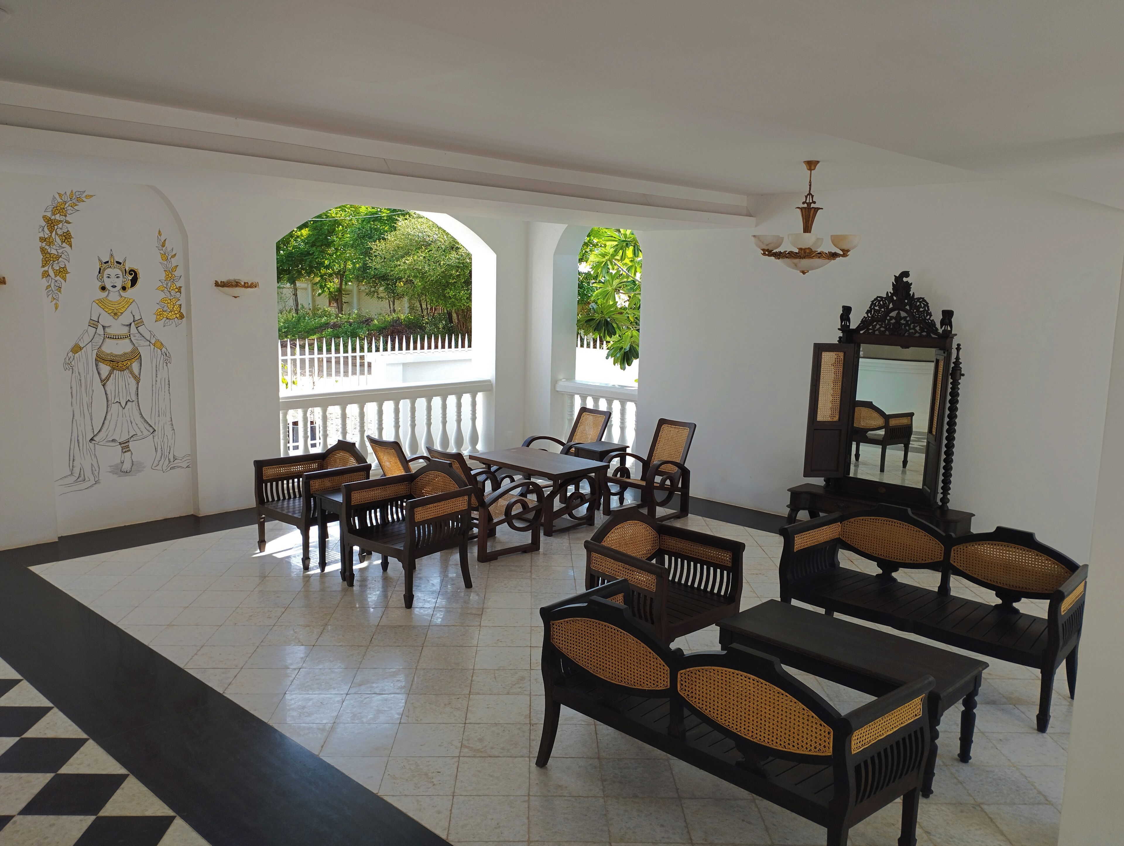A room with a checkered floor, a dining table with chairs, a mirror, and a wall with a decorative mural.