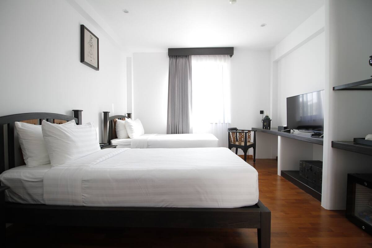 A hotel room with two beds, a TV, and a desk.