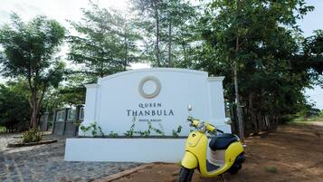 A yellow scooter parked in front of a sign for the Queen Thanbula Hotel Bagan.