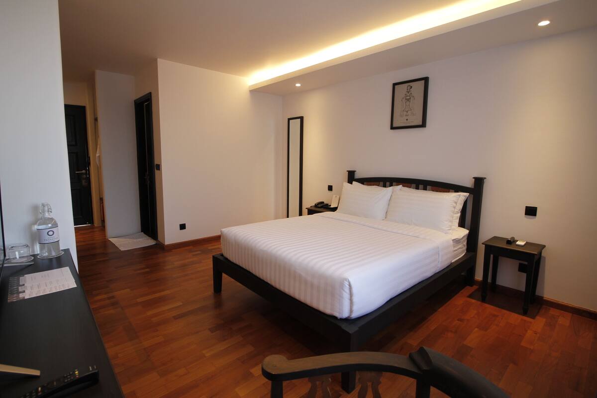 A bedroom with a bed, bedside table, and a desk with a computer and papers.
