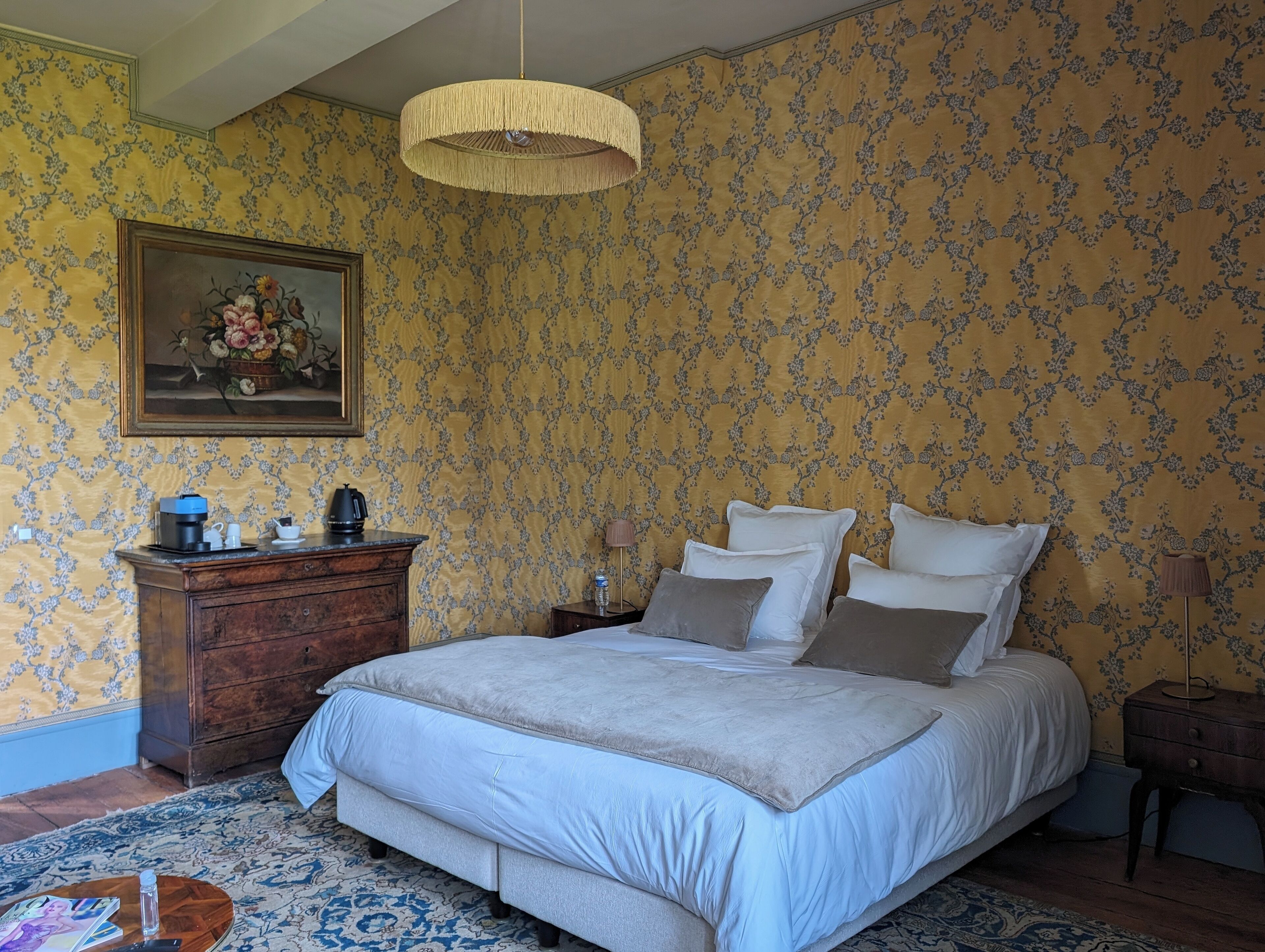 A bedroom with a bed, dresser, and a painting on the wall.