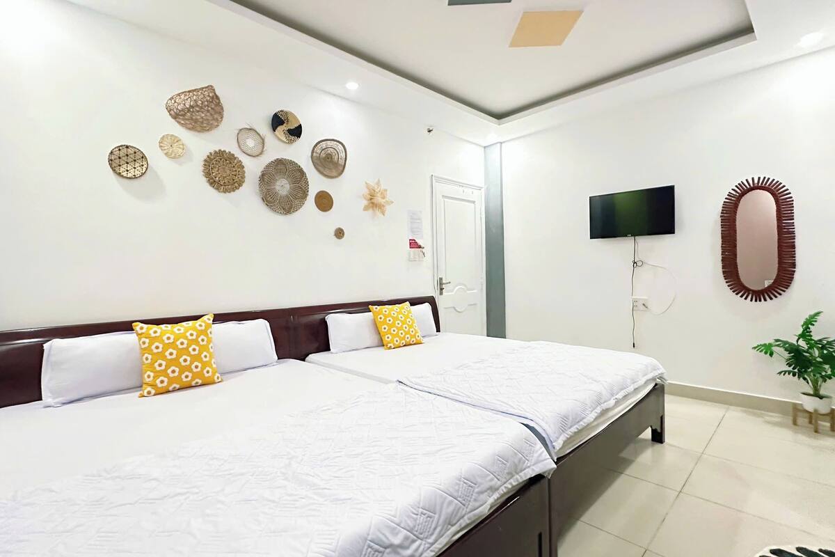 Ein Hotelzimmer mit zwei Betten, einem Fernseher, einem Spiegel und dekorativen Wandbildern.