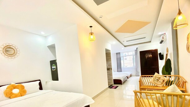 A hotel room with a bed, a wooden chair, a desk, and a window. - Hà Đan Hotel - Bãi Sau Vũng Tàu (Ho Chi Minh City)