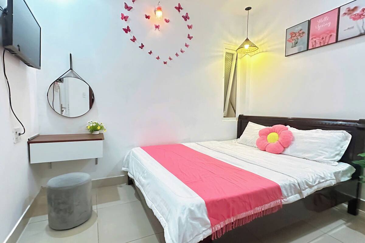 Ein Schlafzimmer mit Bett, Nachttisch, Spiegel, Wand-Fernseher und Dekoration.