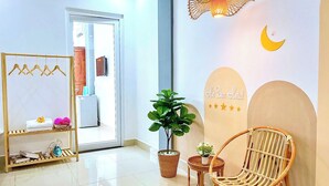 A hotel lobby with a mirror, a hanging light fixture, a wicker chair, and a wall sign. - Hà Đan Hotel - Bãi Sau Vũng Tàu (Ho Chi Minh City)
