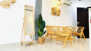 A modern room with a large mirror, wicker furniture, a potted plant, and wall-mounted decorative items. - Hà Đan Hotel - Bãi Sau Vũng Tàu (Ho Chi Minh City)