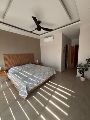 A modern bedroom with a large bed, a ceiling fan, and a potted plant. - Elegant 2BR Marina-view condo (Crucecita)