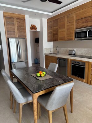 A modern kitchen with wooden cabinets, stainless steel appliances, and a marble countertop. - Elegant 2BR Marina-view condo (Crucecita)