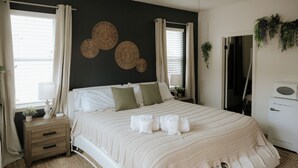 Un dormitorio con cama, mesitas de noche, cómoda y ventana con cortinas.