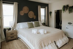 A bed with a white headboard, a bedside table with a lamp, and a wall with circular wall art. - Cozy Vista Suite - Spa Tub & Fire Pit Near LEGOLAND & Safari Park (Vista)