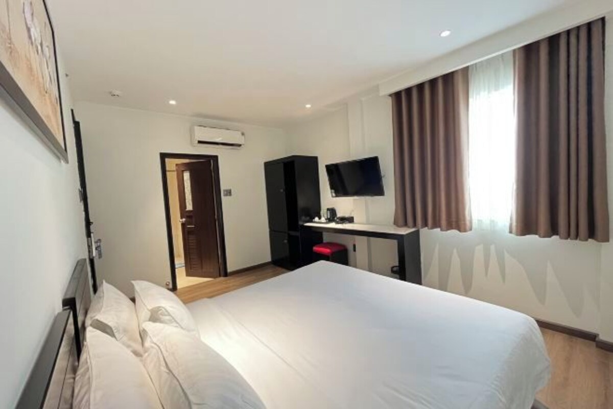 Une chambre d’hôtel équipée d’un lit, d’un bureau avec un ordinateur, d’une télévision et d’un appareil de climatisation.