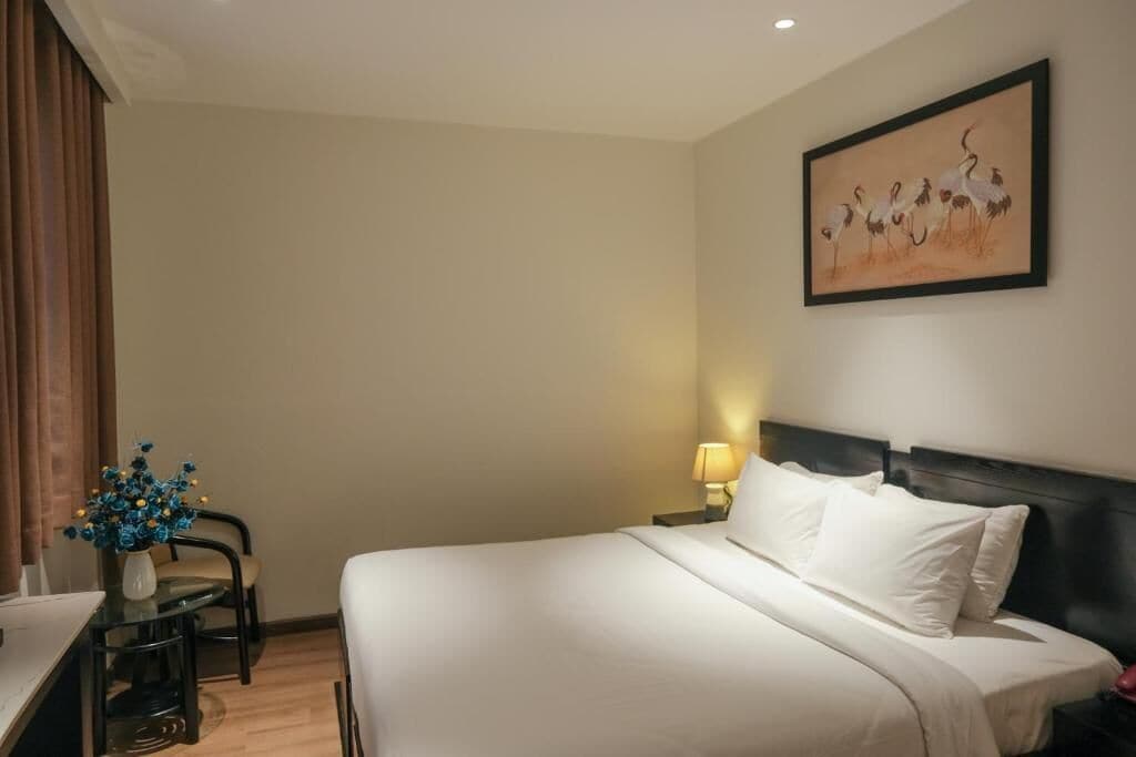 Une chambre d’hôtel avec un lit, un bureau et une chaise, une lampe et un tableau au mur.