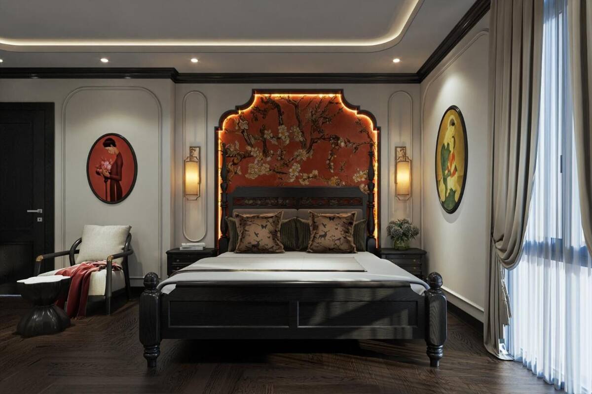 A bedroom with a large bed, a chair, a nightstand, and a wall with a floral headboard.