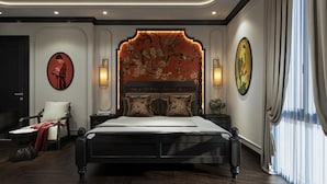 Un dormitorio con una cama grande, un cabecero decorativo, lámparas de pared y una silla con una manta roja.