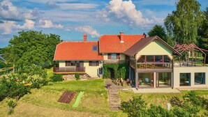 Una casa a due piani con tetto in tegole rosse, un balcone e un'ampia finestra in vetro.