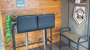 Un mur en bois sur lequel est fixée une plaque métallique portant l’inscription « La rivière est mon endroit préféré », une chaise en métal, un tabouret en métal et une pancarte de bienvenue.