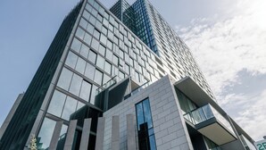 Un moderno edificio de rascacielos con ventanas de vidrio reflectante y una entrada destacada de fachada blanca.