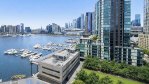 Un edificio alto con un puerto deportivo al frente y un horizonte urbano al fondo.