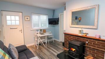 A living room with a fireplace, a television, a dining table, and a sofa.