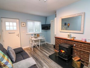 Ein Wohnzimmer mit Kamin, Fernseher, Esstisch und einer Couch.
