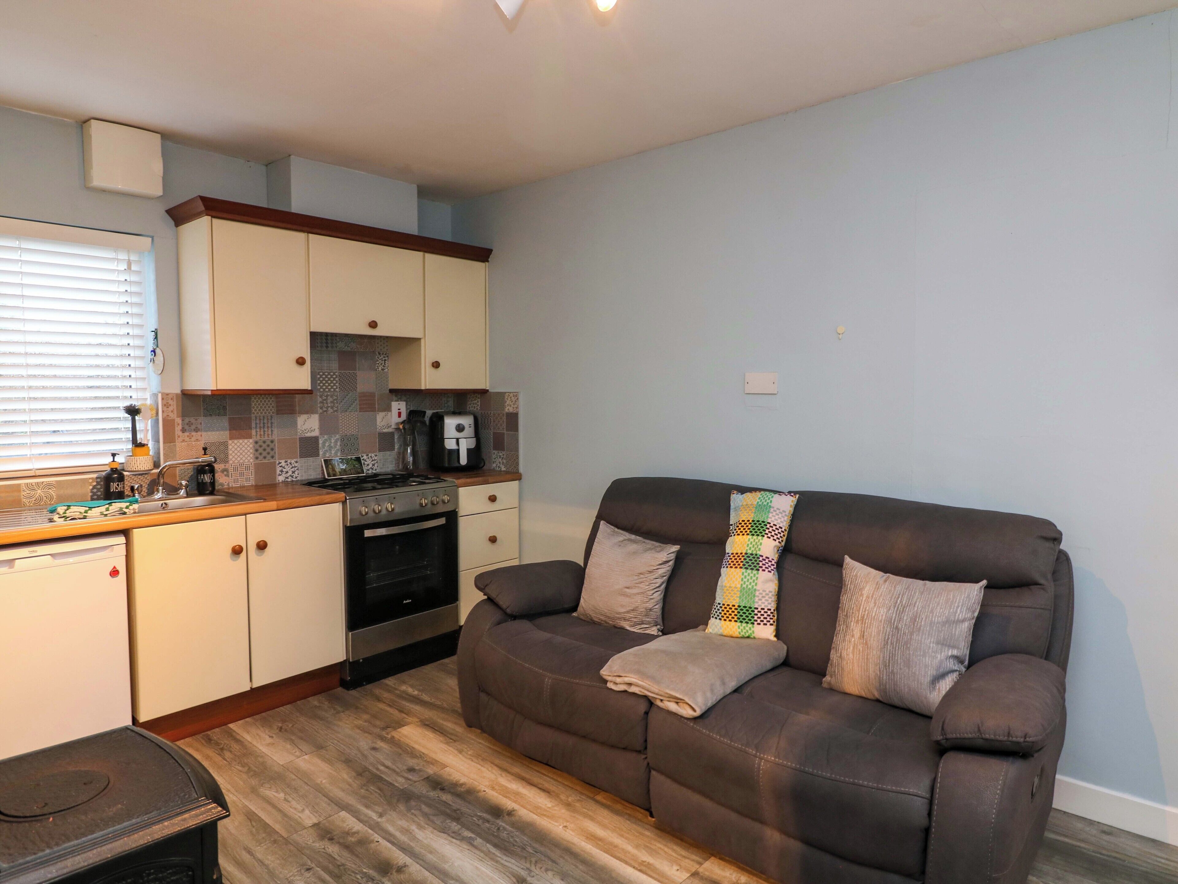 A compact living space with a kitchenette, a sofa, and a small table.