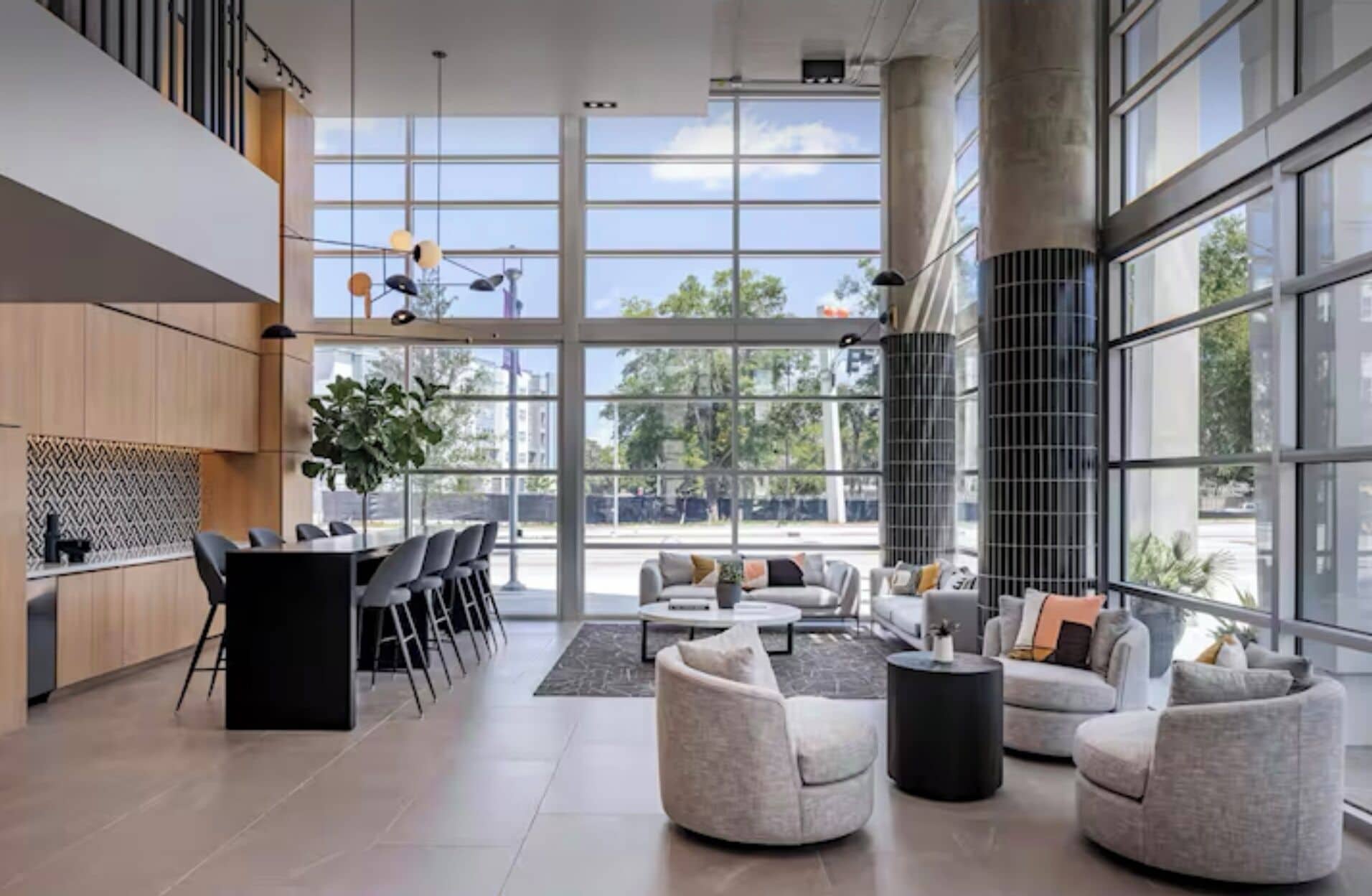 Eine geräumige Lobby mit modernem Design, ausgestattet mit einer großen Sitzecke, einer Küche und großen Fenstern mit Blick ins Freie.