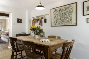 Ein Essbereich mit einem Holztisch, vier Stühlen, einer Blumenvase und einer Hängelampe.